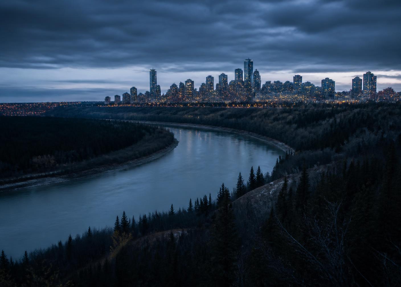 The North Saskatchewan river valley curving below the Edmonton skyline at blue hour.